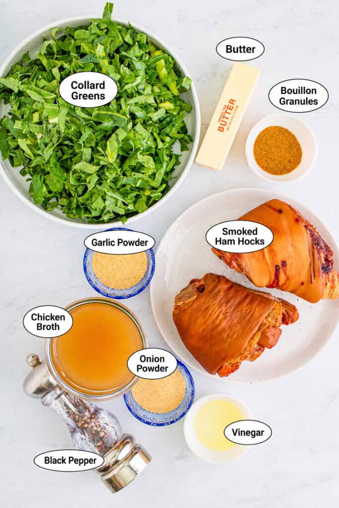 Top down ingredient layout for Southern Collard Greens Recipe: chopped greens, two ham hocks, butter, chicken stock, garlic powder, onion powder, and seasonings.