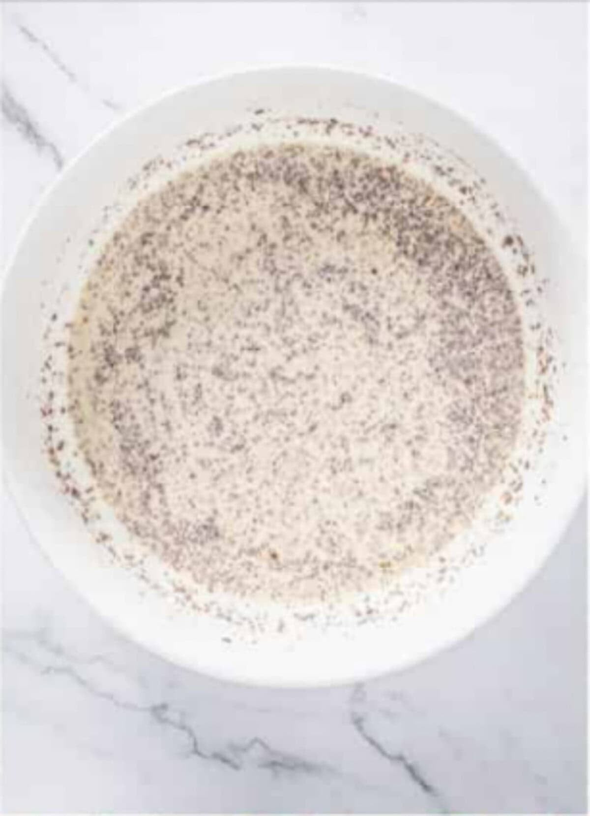 Beaten egg, heavy cream, cinnamon, and nutmeg whisked together in a small bowl for Rice Pudding Recipe.