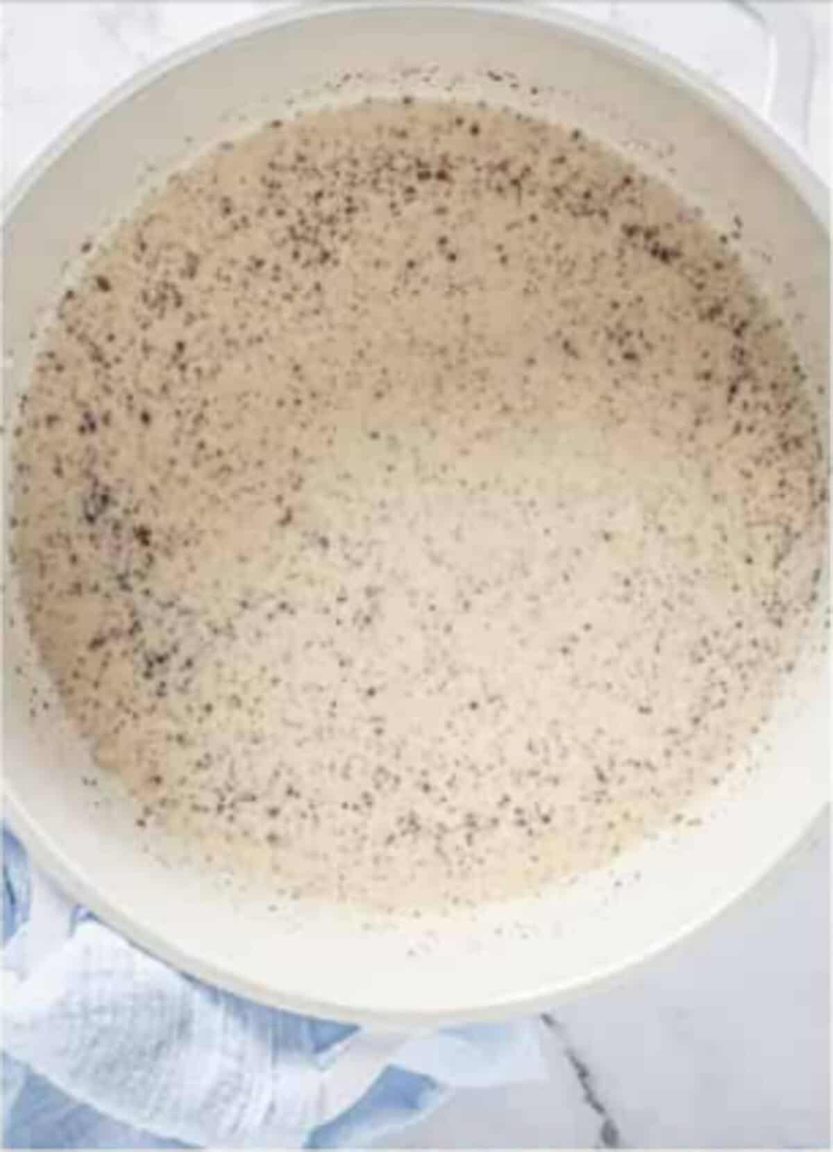 Rice mixture in a saucepan with cinnamon flecks after the egg cream mixture has been streamed in for Rice Pudding Recipe.