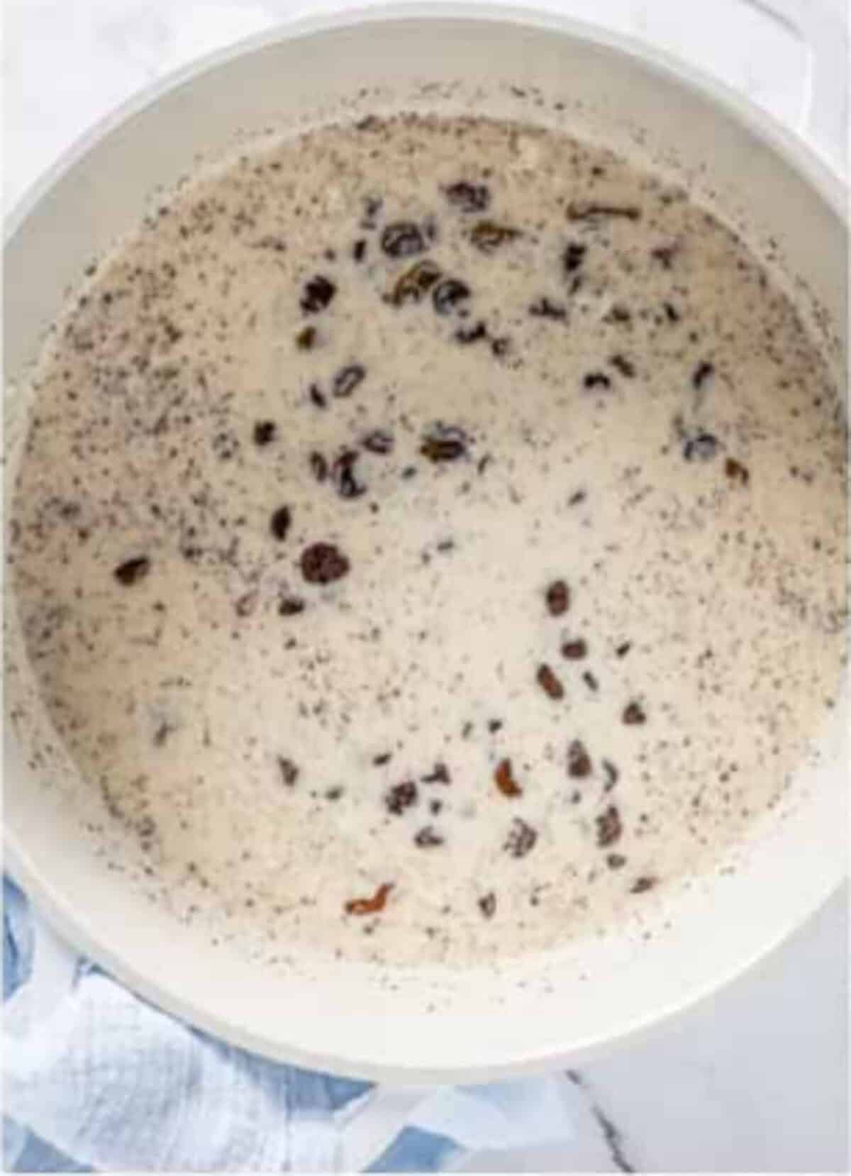 Golden raisins and regular raisins added on top of the creamy Rice Pudding Recipe mixture in the saucepan.