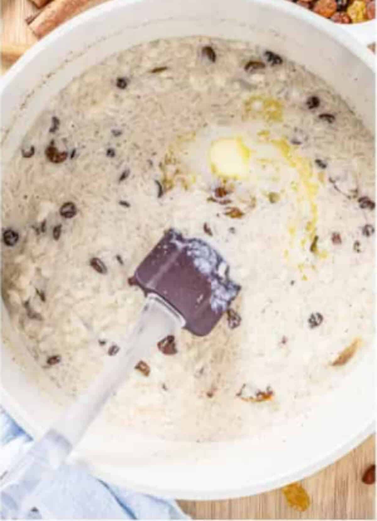 Creamy Rice Pudding Recipe with raisins folded in and a pat of butter ready to stir at the end of cooking.