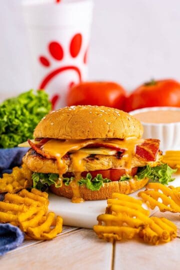 Finished Copycat Chick Fil A Grilled Chicken Sandwich Recipe layered with bacon, cheese, lettuce, and tomato on a multigrain bun.