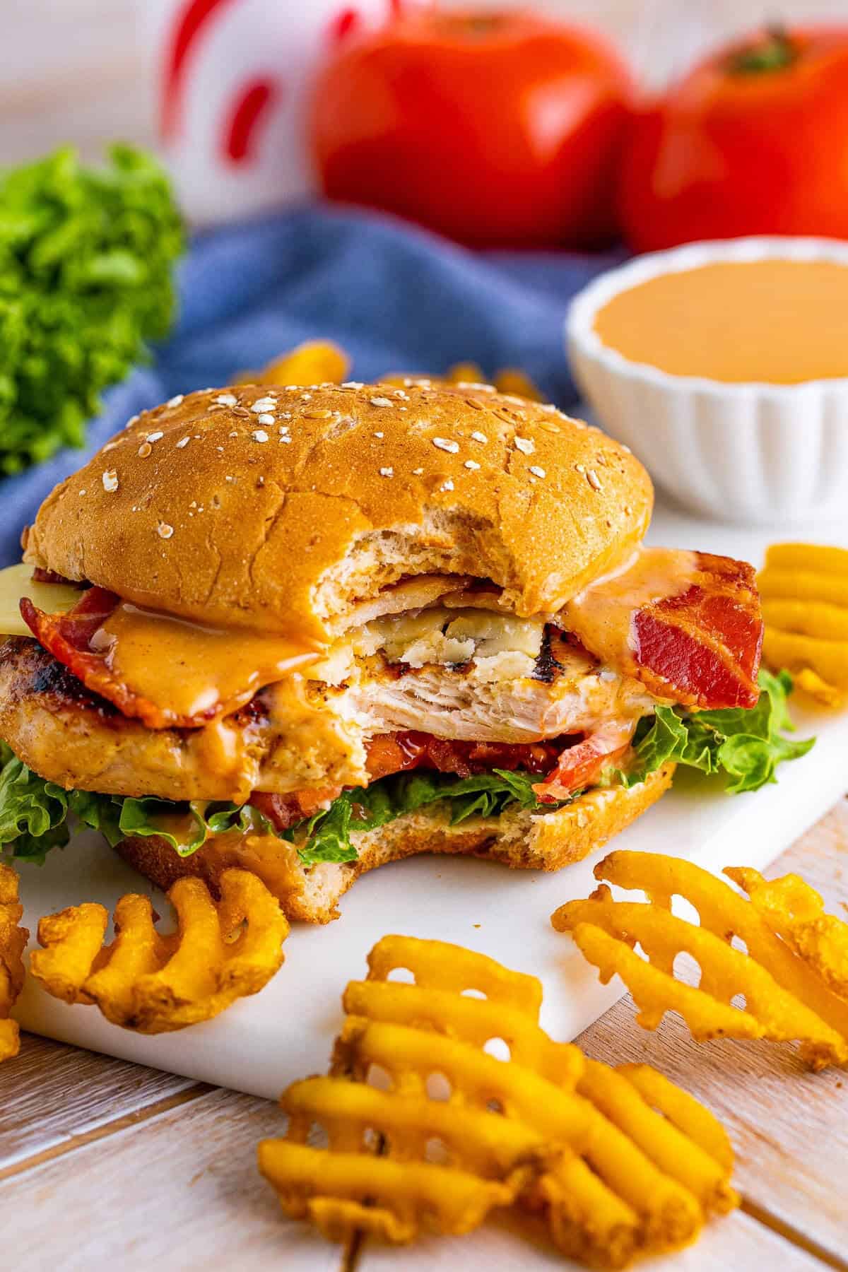 Bite shot of a copycat Chick Fil A grilled chicken club sandwich showing the grilled chicken bacon and melty pepper jack cheese.