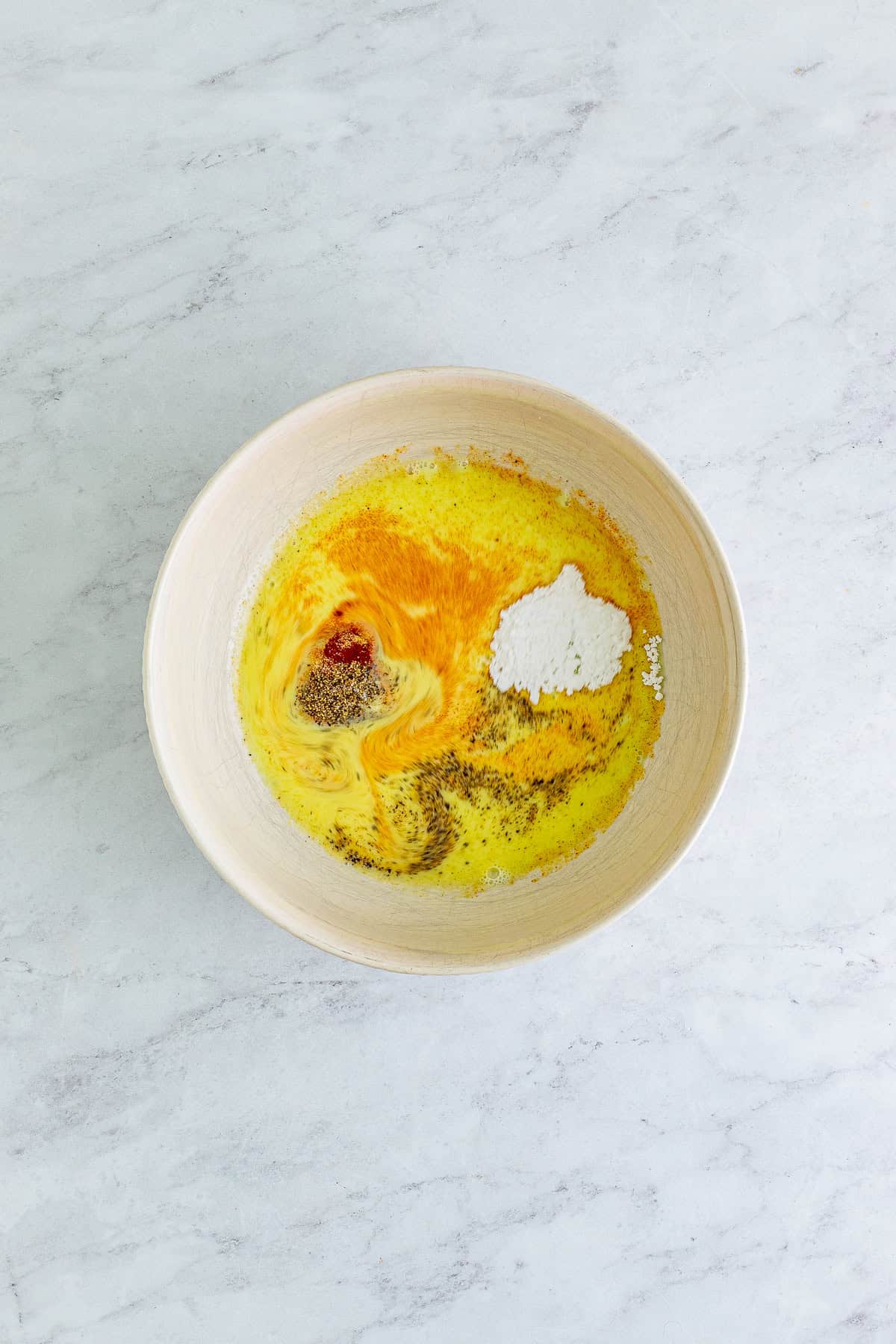 Chick Fil A pickle juice marinade whisked in a bowl with paprika and seasoning.