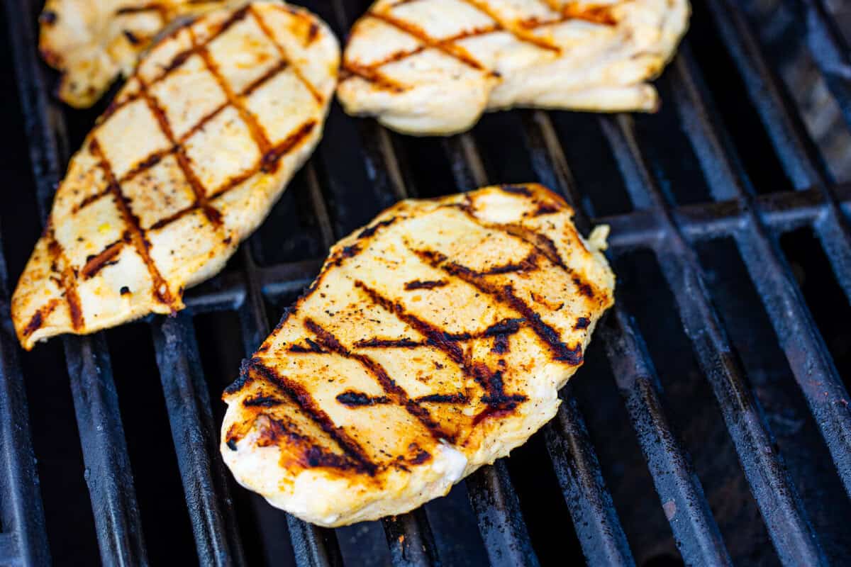 Assembled copycat Chick Fil A grilled chicken club sandwich on a cutting board with the honey roasted bbq sauce drizzle.