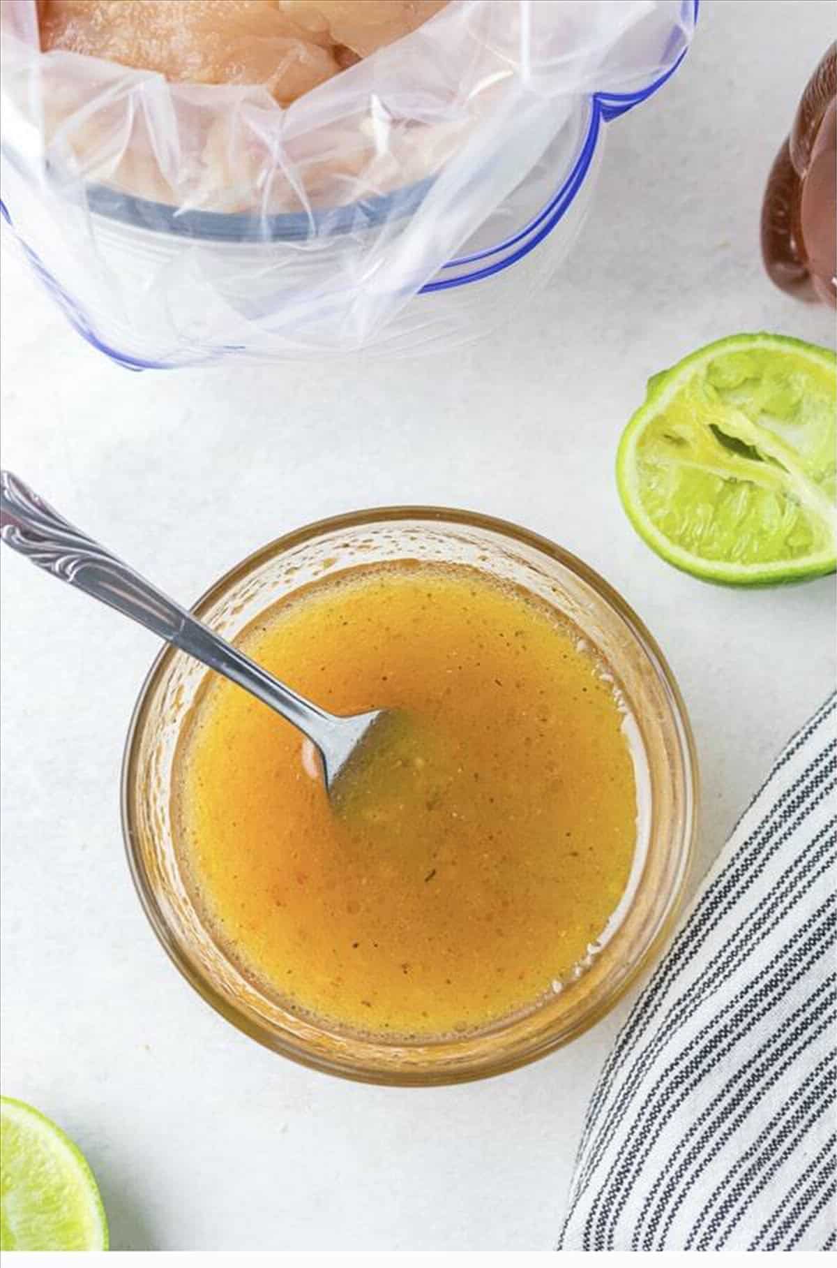 Italian dressing marinade with honey and lime juice whisked in a small glass bowl with a spoon for Cracker Barrel Chicken Tenders.