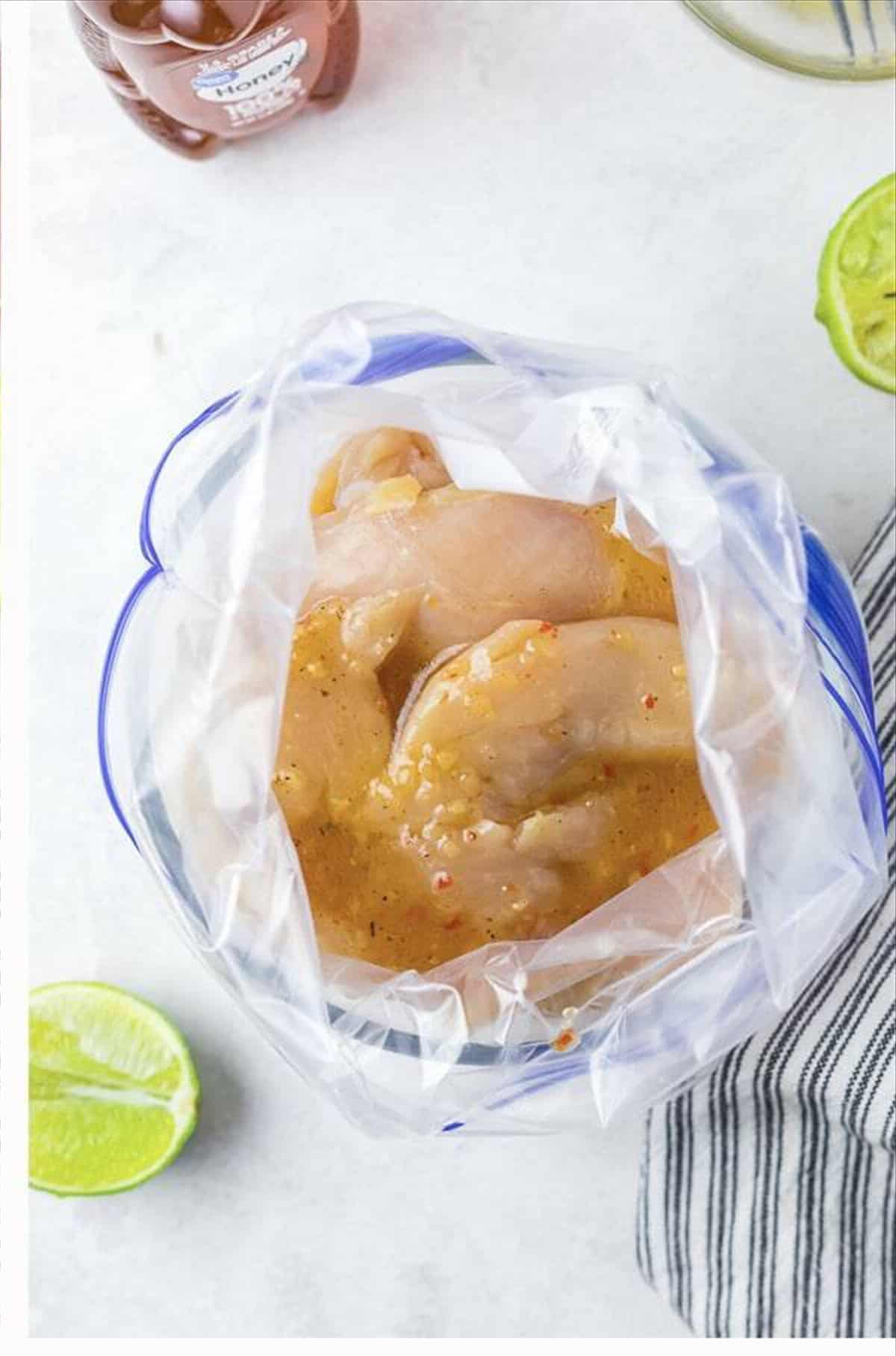 Raw chicken tenderloins coated in honey lime marinade inside a clear zip lock bag for Cracker Barrel Chicken Tenders.