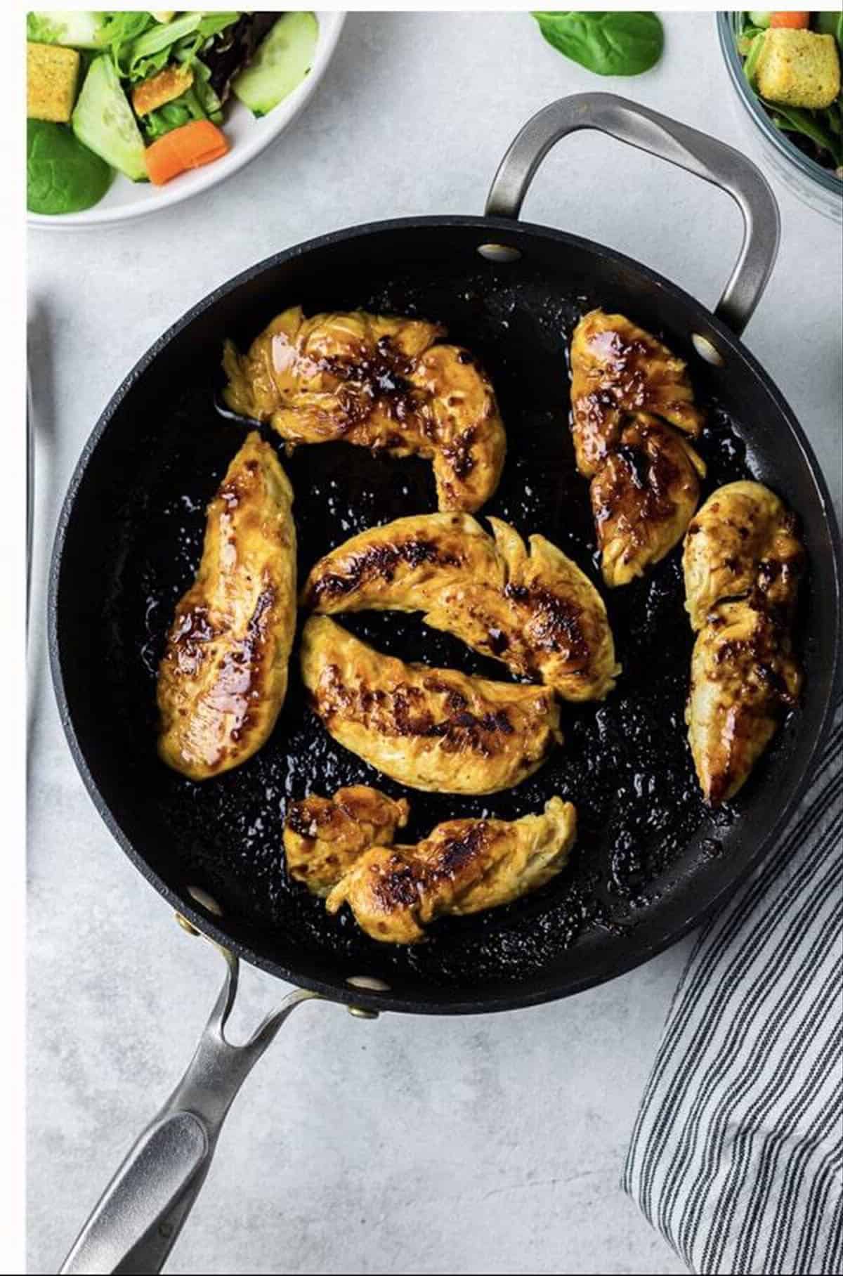 Golden browned Cracker Barrel Chicken Tenders fully cooked in a dark skillet with caramelized edges and grill marks.