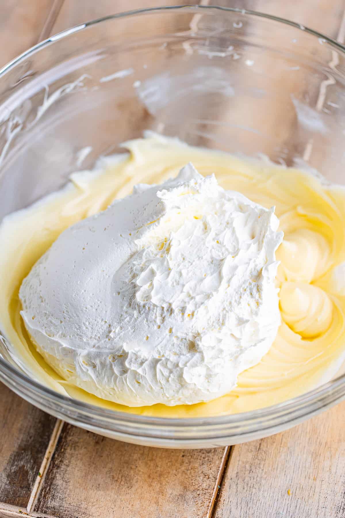 Cool Whip dollop sitting on top of the smooth cream cheese mixture before folding for the Cream Cheese Fruit Dip recipe.