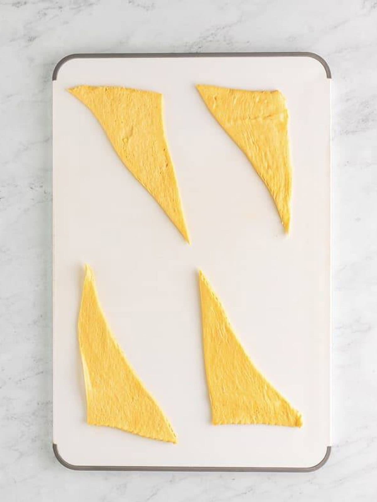 Crescent roll dough triangles laid out on a baking sheet.