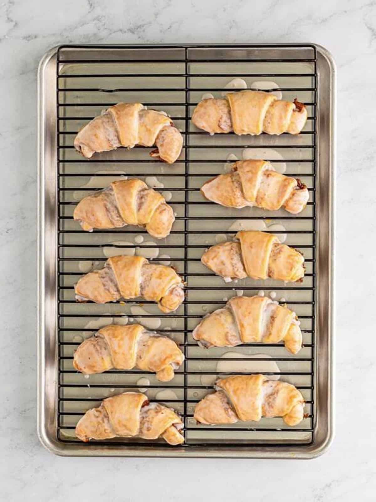 Glazed crescent roll cinnamon rolls cooling on a wire rack.