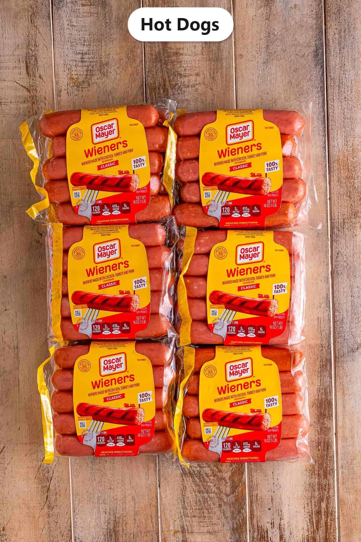 Labeled ingredients flat lay showing six packages of Oscar Mayer Wieners hot dogs on a cutting board for the Easy Crockpot Hot Dogs Recipe.