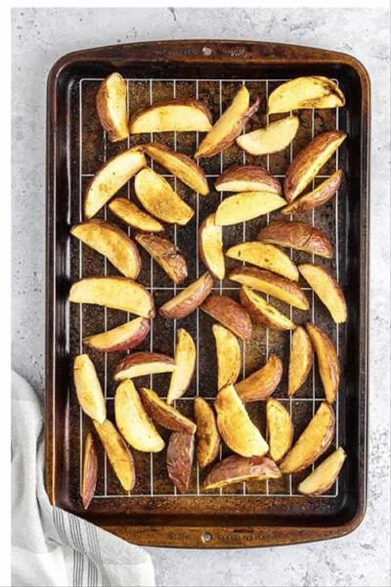 Golden crispy Deep Fried Potato Wedges draining on a wire rack after the second fry.