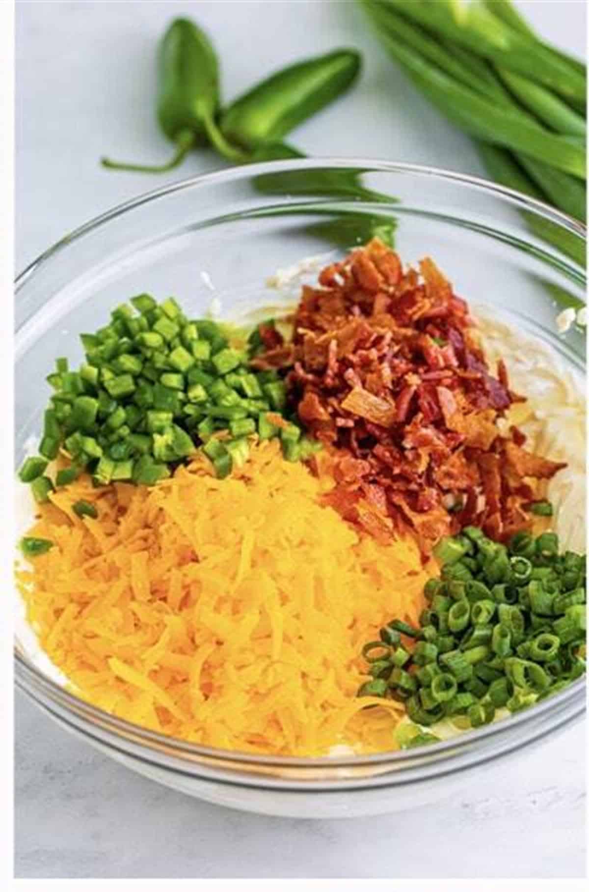 Shredded cheddar, chopped jalapenos, crumbled bacon, and sliced scallions added to whipped cream cheese for Easy Cream Cheese Pinwheels (Jalapeno Popper).