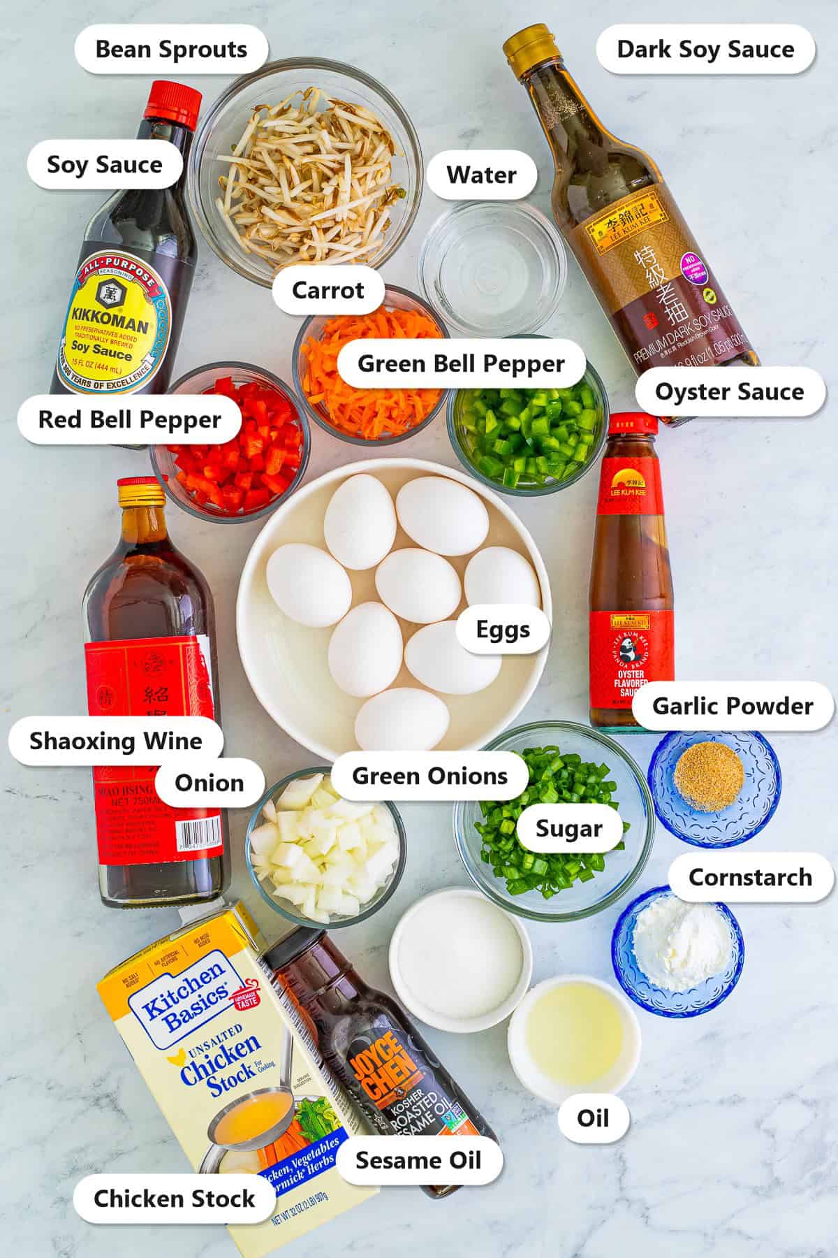 Labeled ingredients needed to make egg foo young including eggs, bean sprouts, soy sauce, dark soy sauce, oyster sauce, Shaoxing wine, bell peppers, carrot, onion, green onions, cornstarch, and sesame oil.