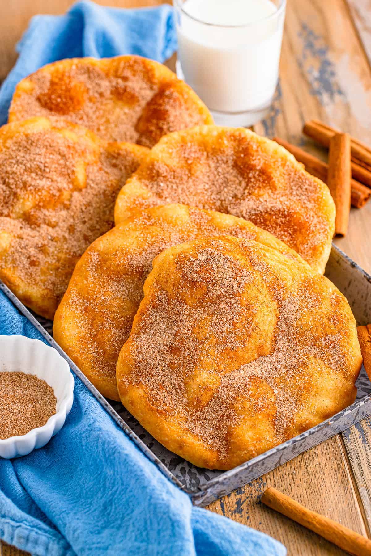 Stack of homemade Elephant Ears coated in cinnamon sugar on a wooden board.