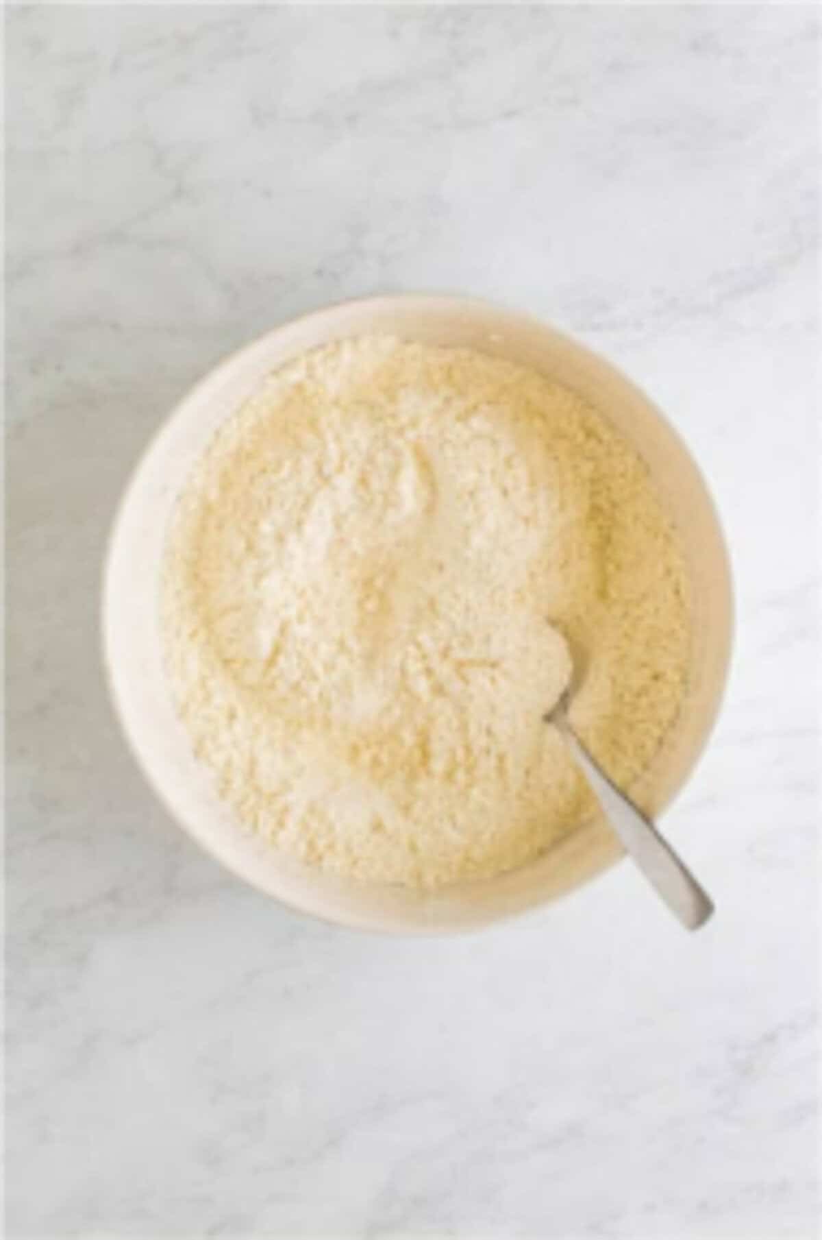 Warm milk added to flour mixture being stirred into a slightly sticky dough for Homemade Elephant Ears.