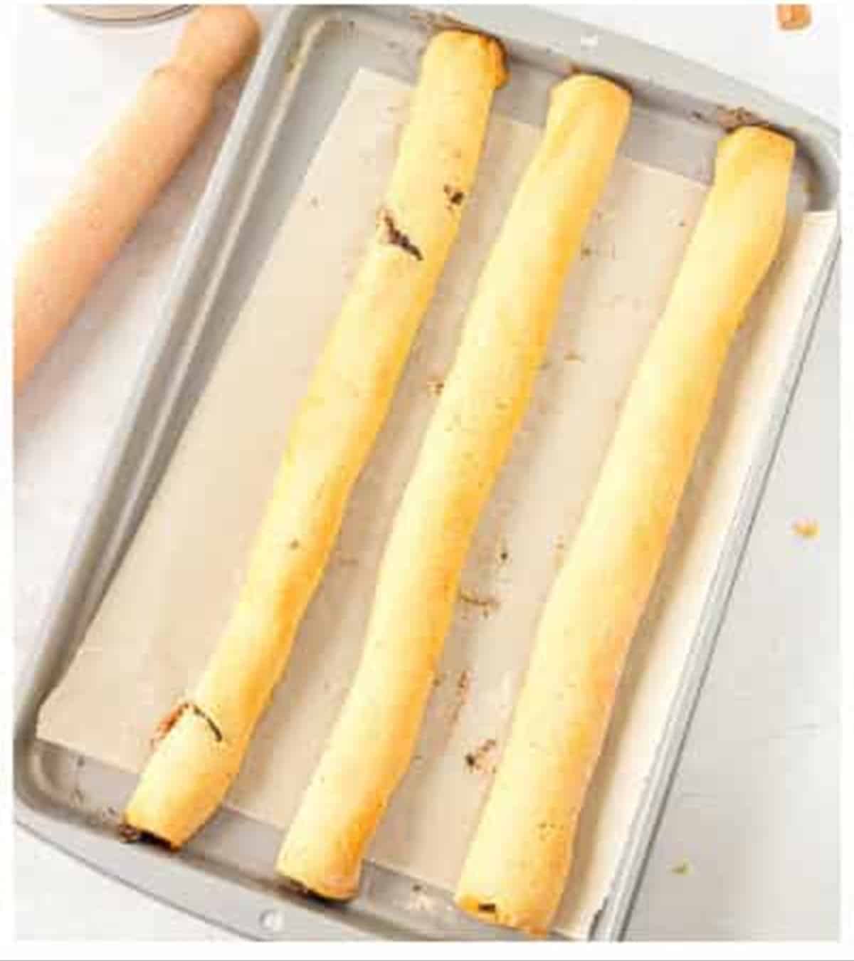 Filled fig newton dough rolled into logs on a baking sheet.
