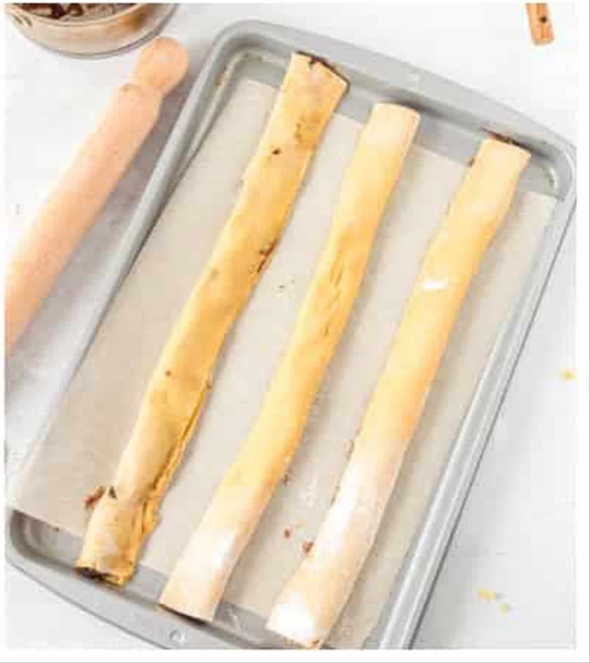 Baked fig newton logs on a baking sheet ready to slice.