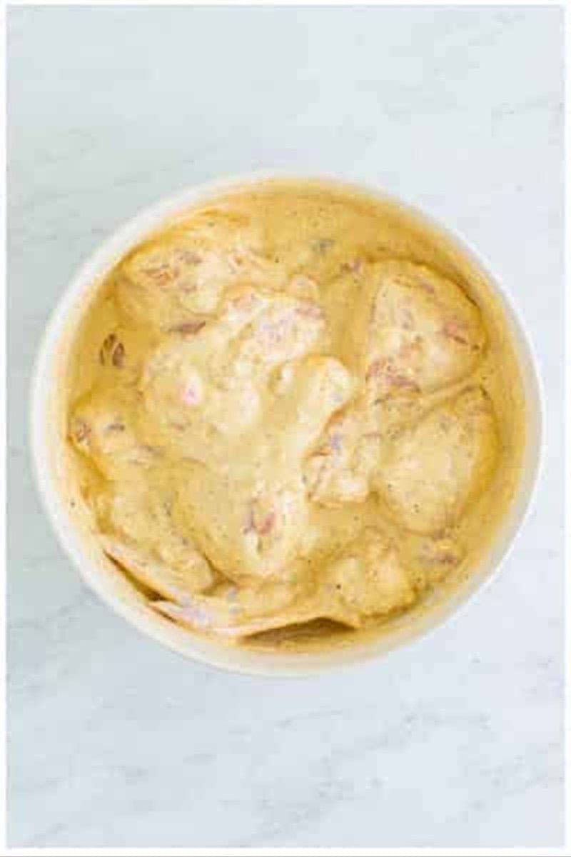 Chicken pieces in a thin pancake like batter after water is added to the flour coating.