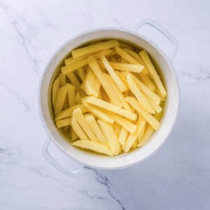 Cut Homemade French Fries soaking in cold water then drying with a clean kitchen towel.