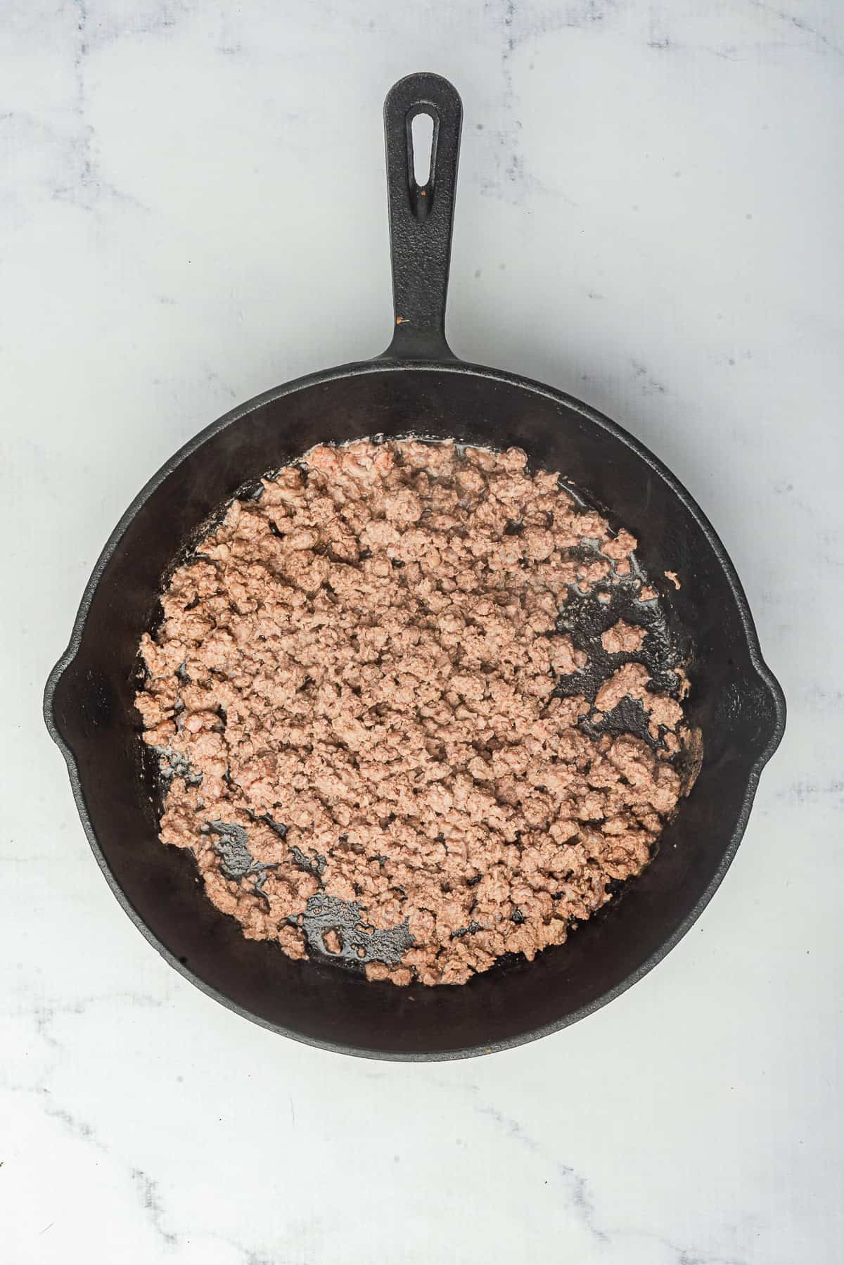 Ground beef cooked down into a finely textured base in the skillet, ready for the Hot Dog Sauce spices and condiments.
