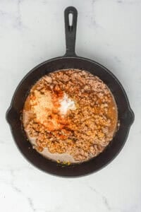 Ketchup, mustard, sugar, vinegar, Worcestershire sauce, and Coney Sauce Recipe spices added to the cooked beef in the pan.