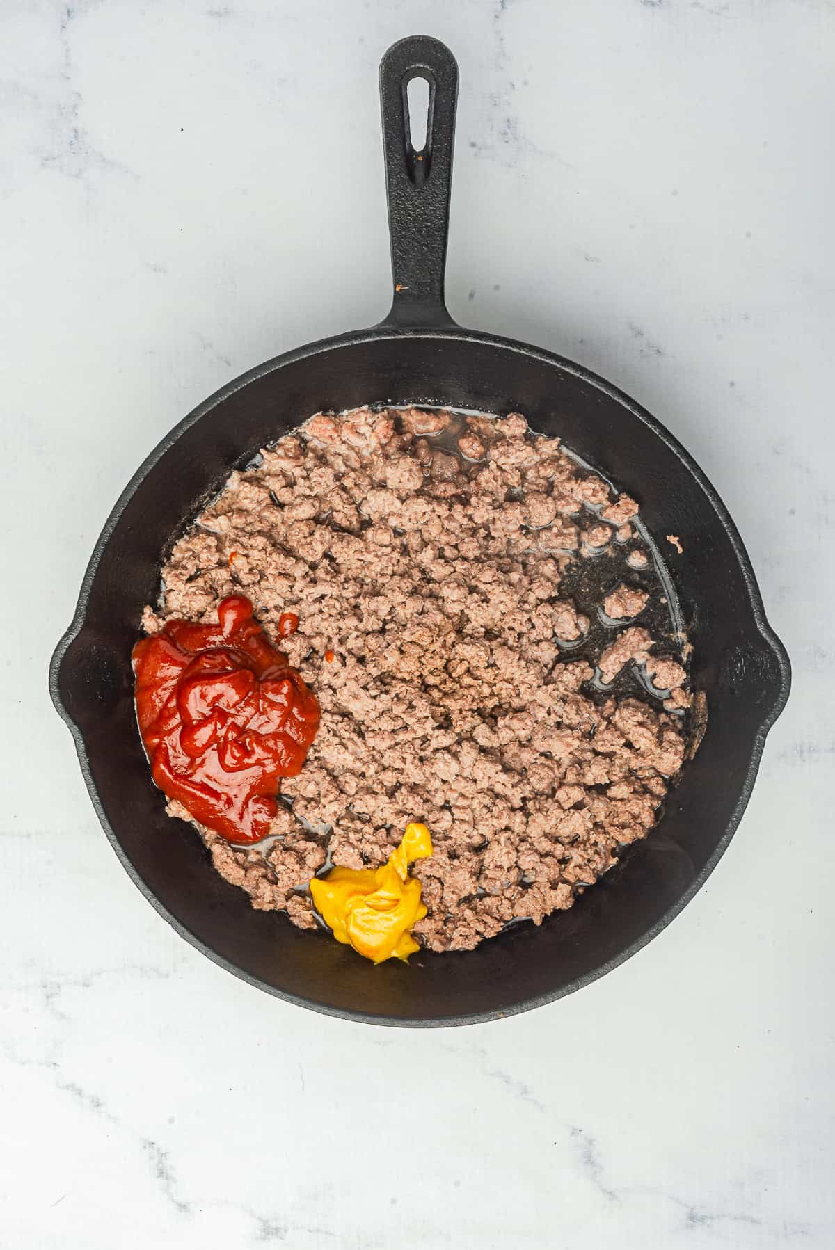 Hot Dog Sauce simmering in the pan after the sauce and spices are stirred in, beef evenly coated and starting to thicken.