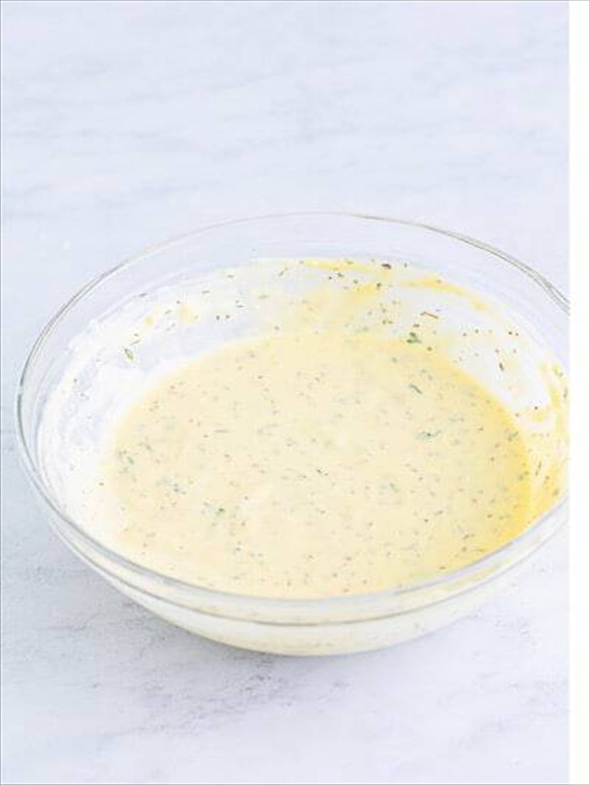 The creamy Italian dressing whisked together in a glass bowl for Italian sliders.