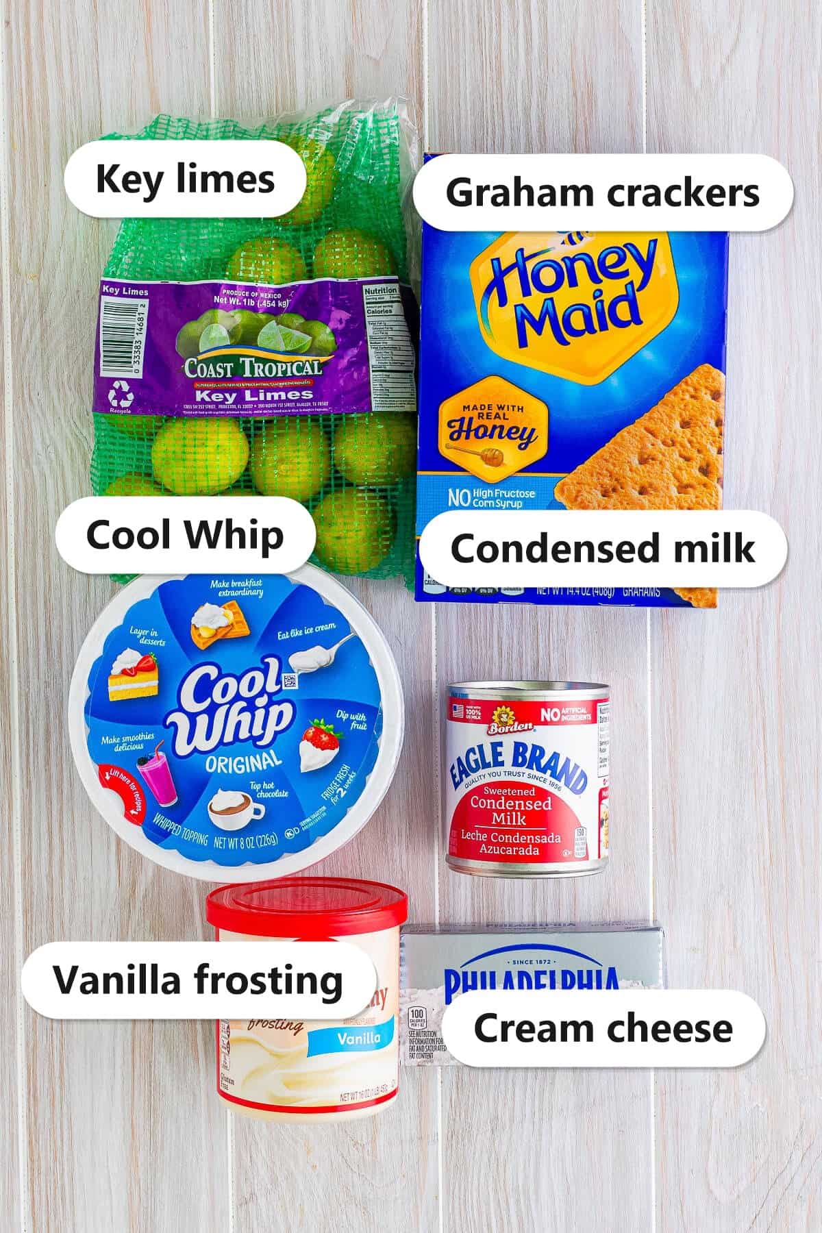 Labeled key lime eclair cake ingredients including key limes, graham crackers, Cool Whip, condensed milk, vanilla frosting, and cream cheese.