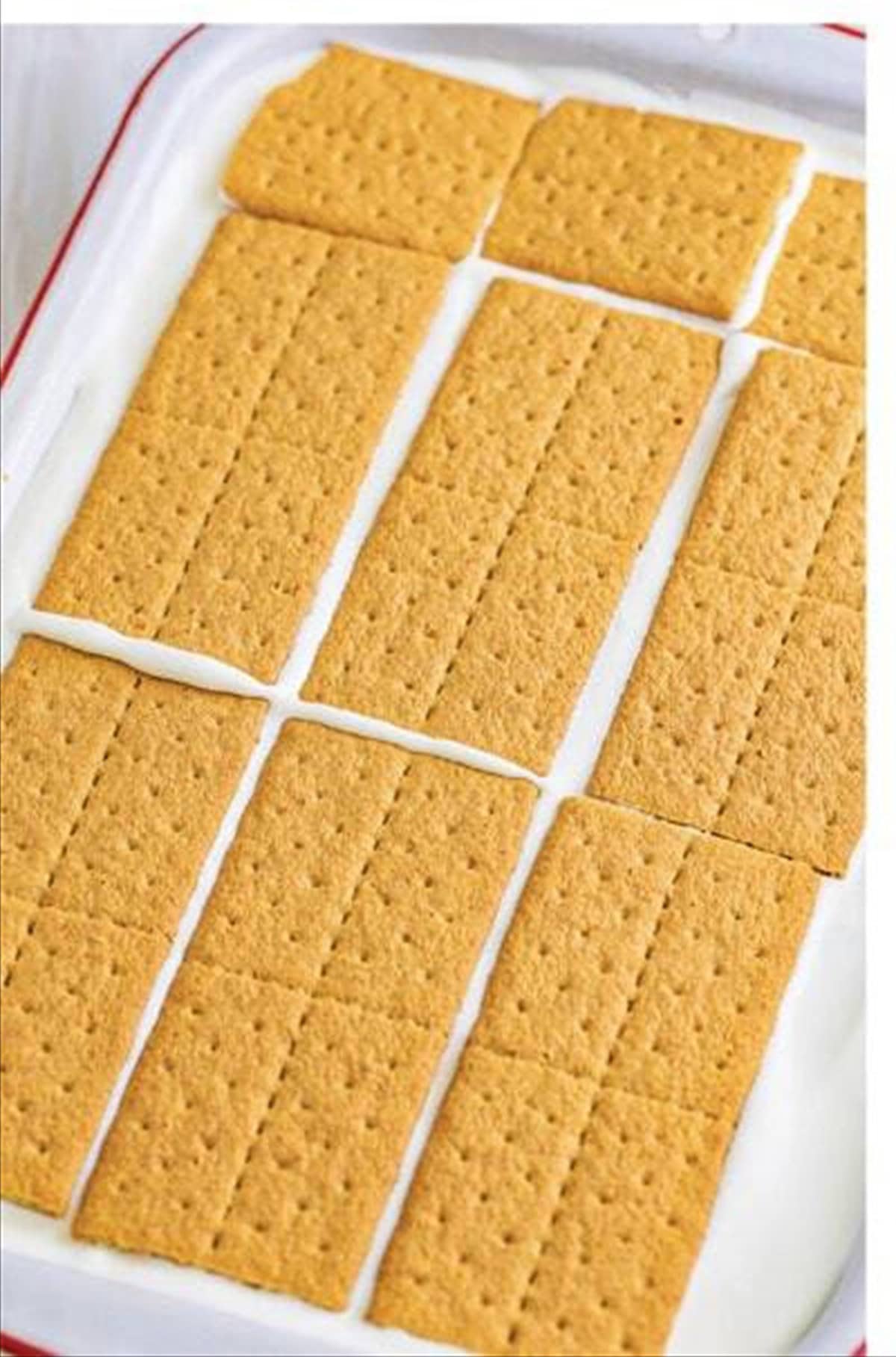 Top layer of graham crackers added to key lime eclair cake in a 9x13 pan.
