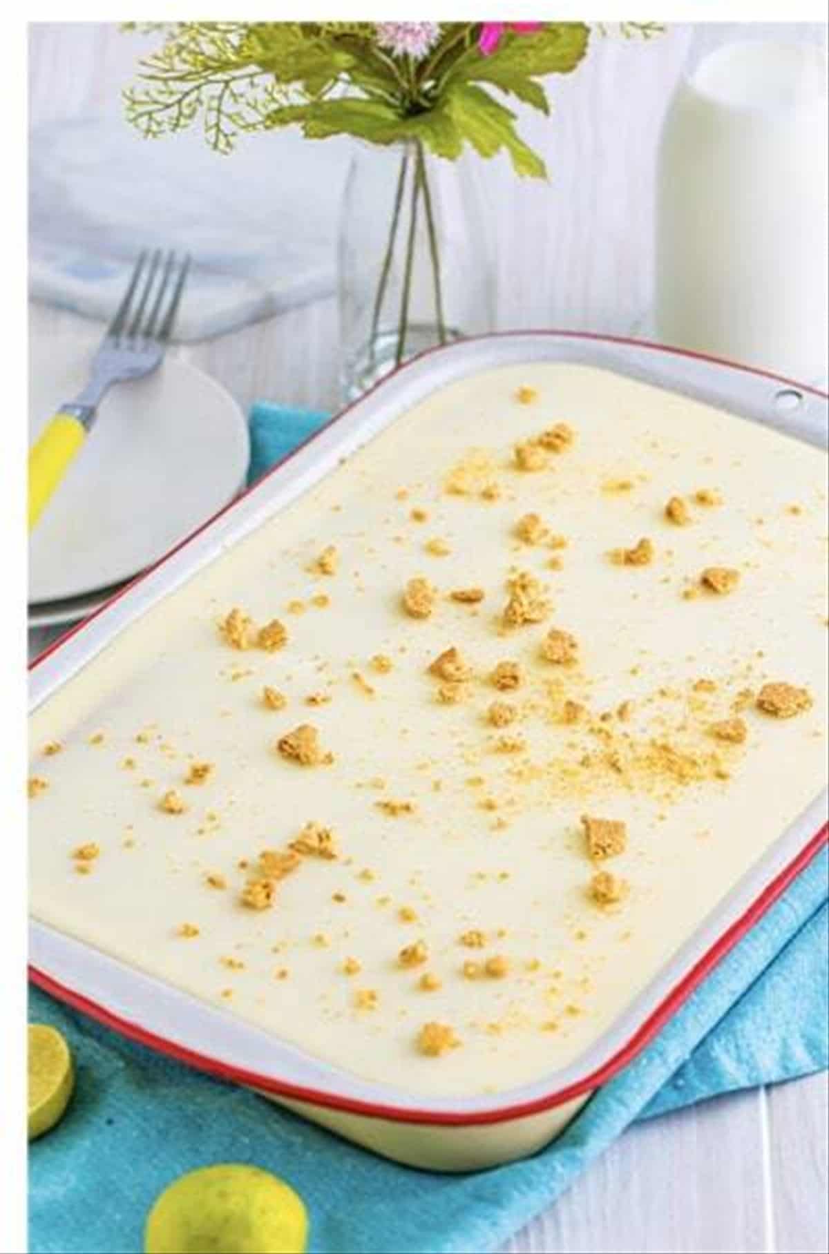 Finished key lime eclair cake topped with graham cracker crumbs in a red trim pan.