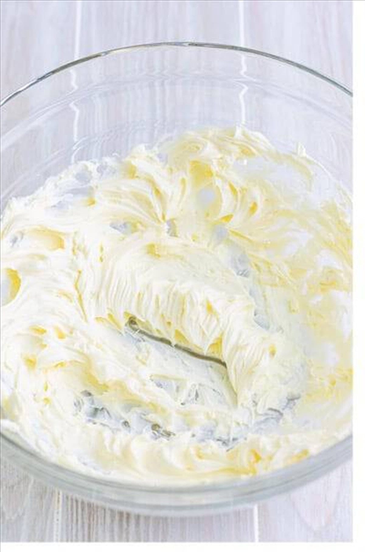 Cream cheese whipped smooth in a glass bowl for key lime eclair cake filling.