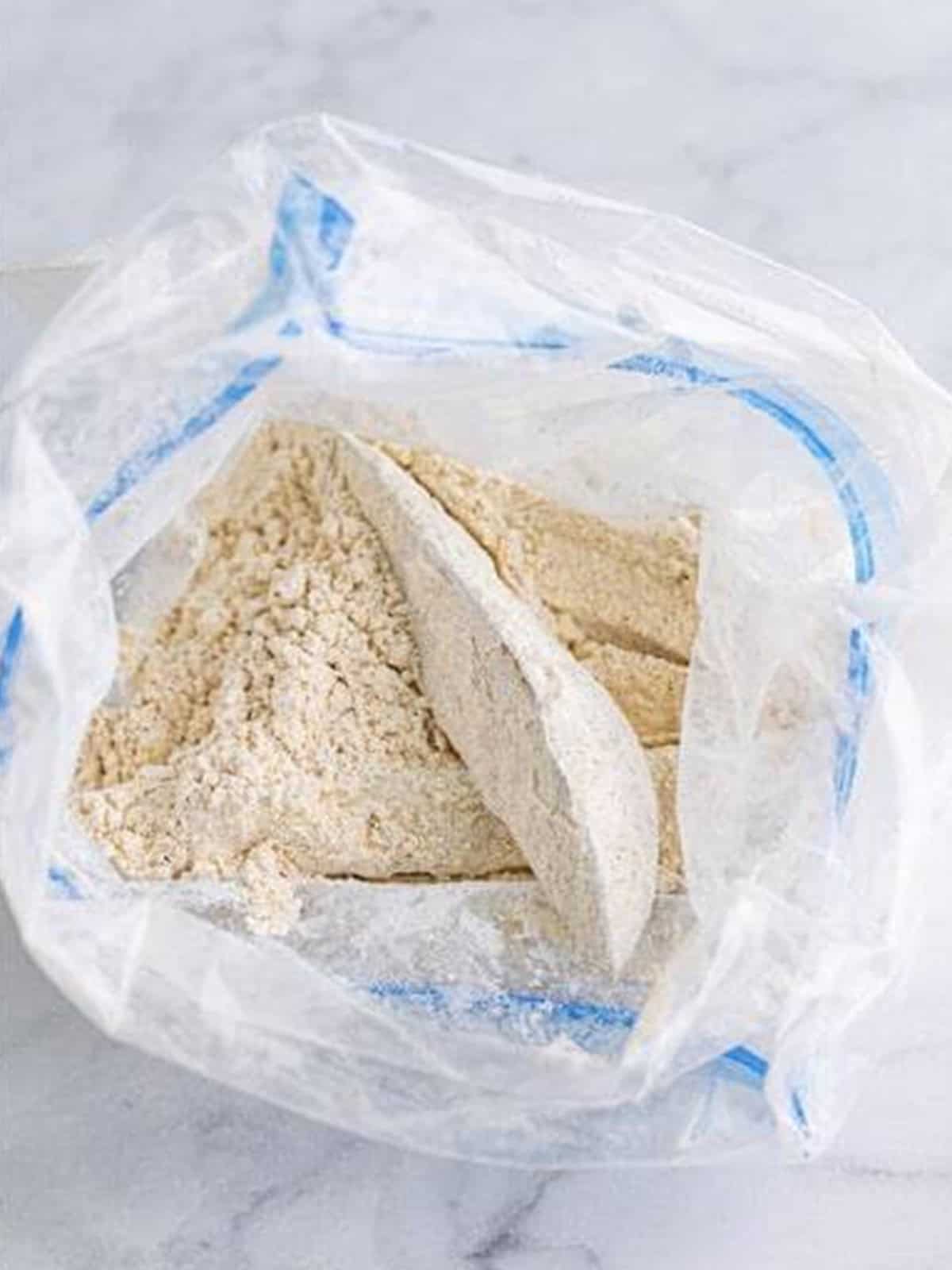 Potato wedges tossed in seasoned flour in a bag for KFC potato wedges.
