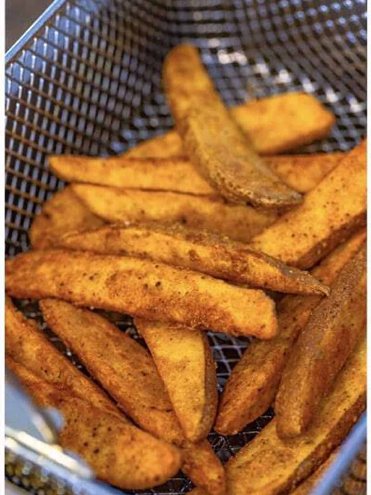 Potato wedges in a fry basket during the first fry for KFC potato wedges.