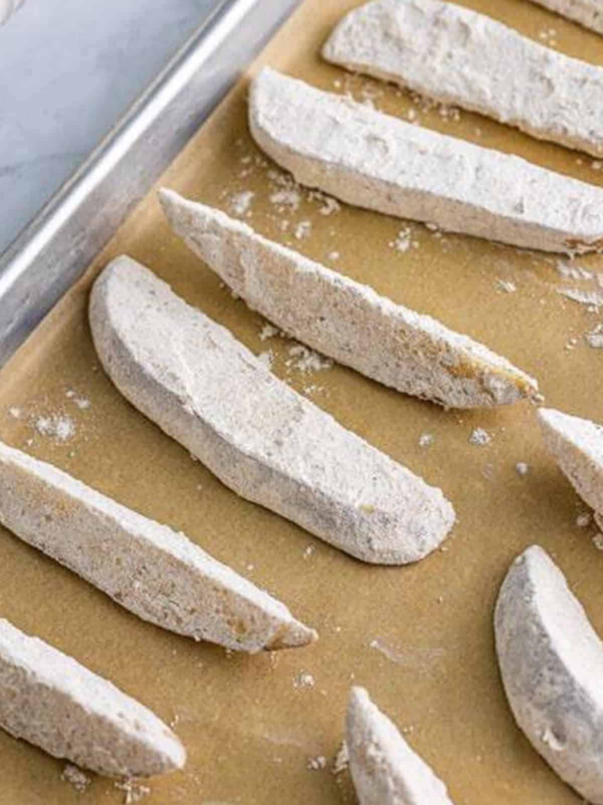 Floured potato wedges laid out on a parchment lined tray for KFC potato wedges.