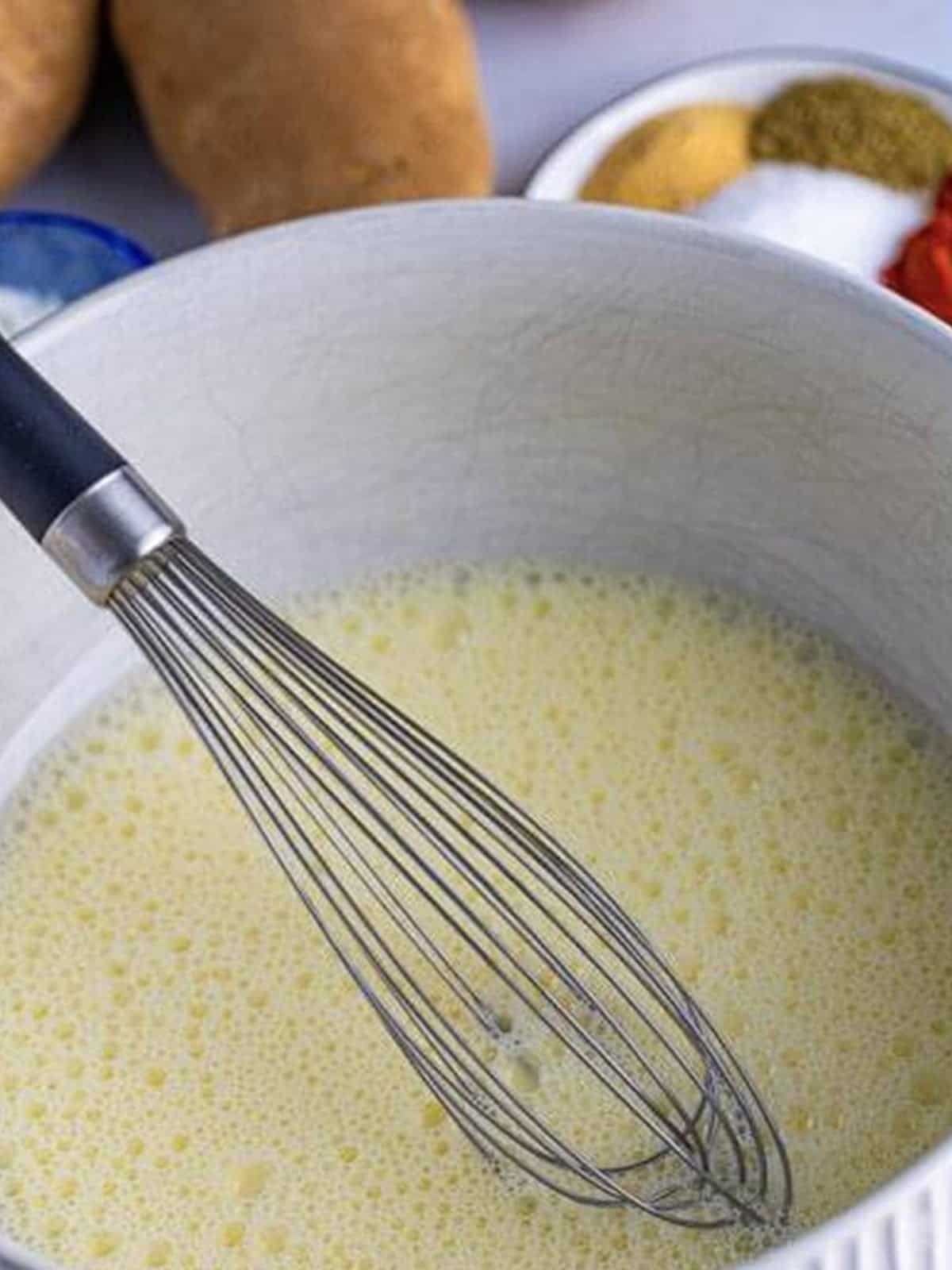 Whisking milk and egg in a bowl for KFC potato wedges.