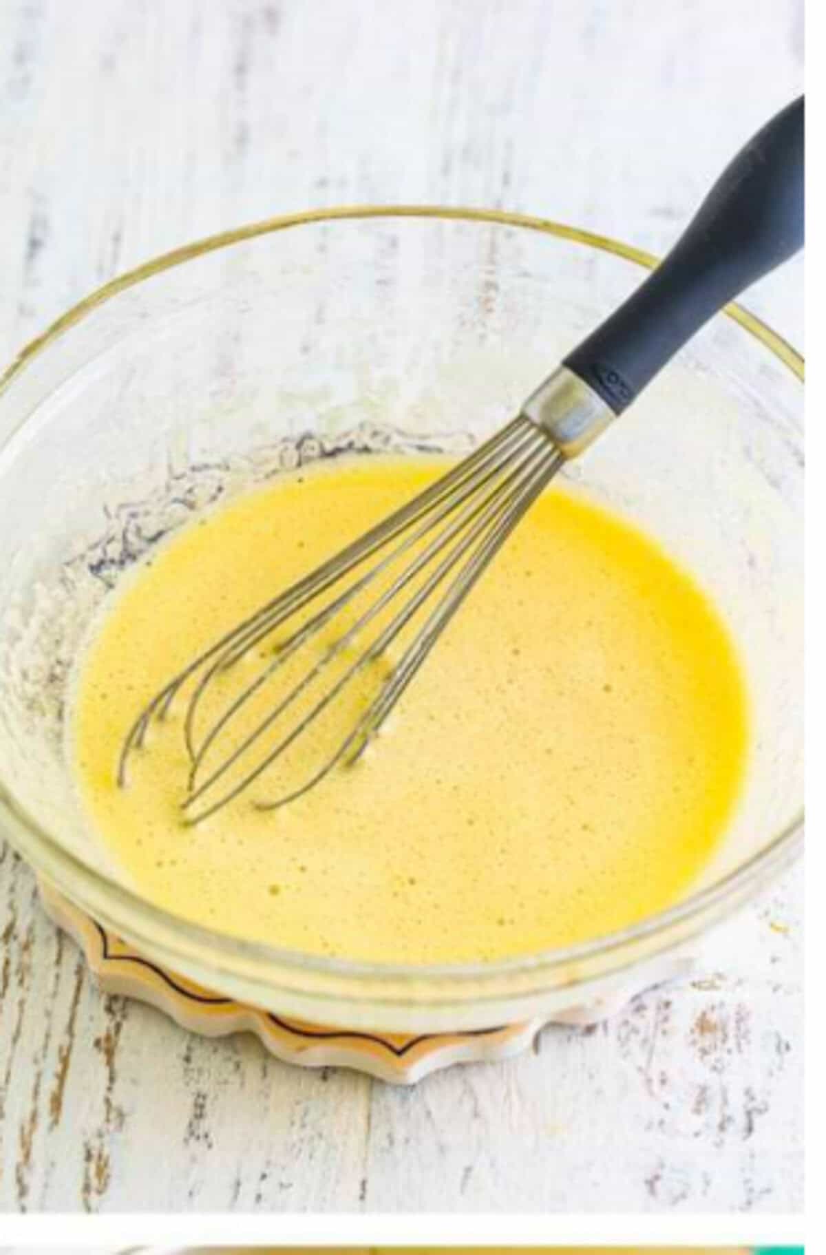 A heatproof bowl set over a saucepan of simmering water as a double boiler with the egg and sugar mixture being whisked constantly for the Homemade Lady Finger Cookies Recipe.