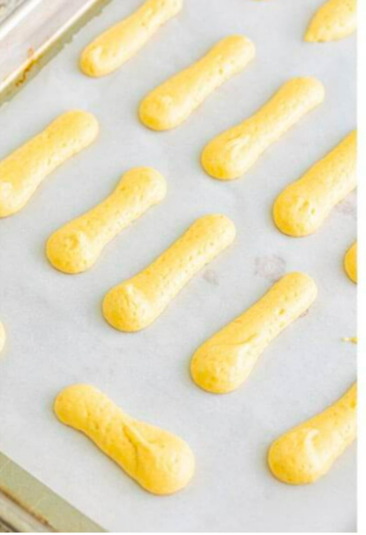 Sifted flour and cornstarch being gently folded into the whipped egg foam with a spatula until just combined for the Homemade Lady Finger Cookies Recipe.