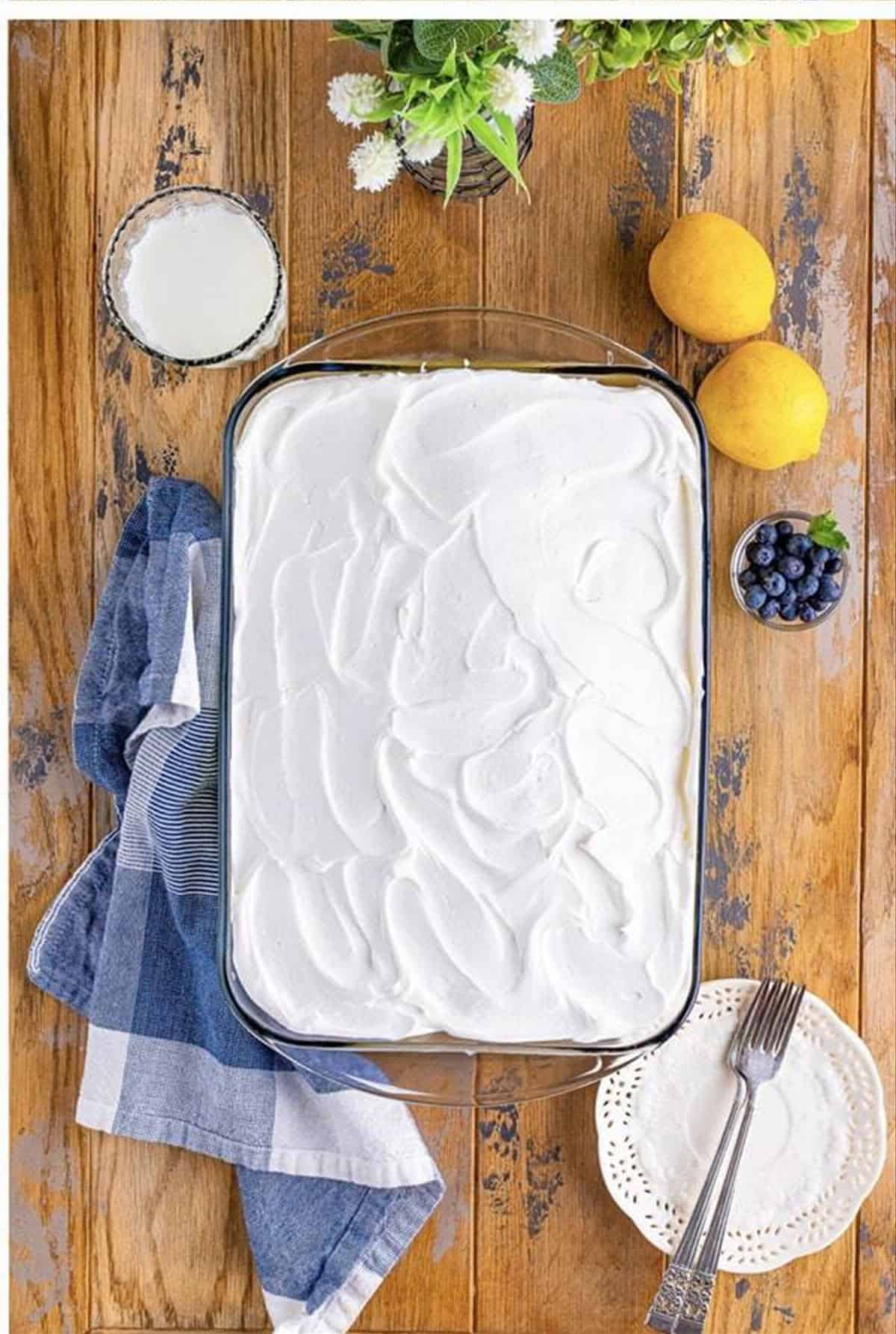 Lemon blueberry poke cake topped with whipped topping.
