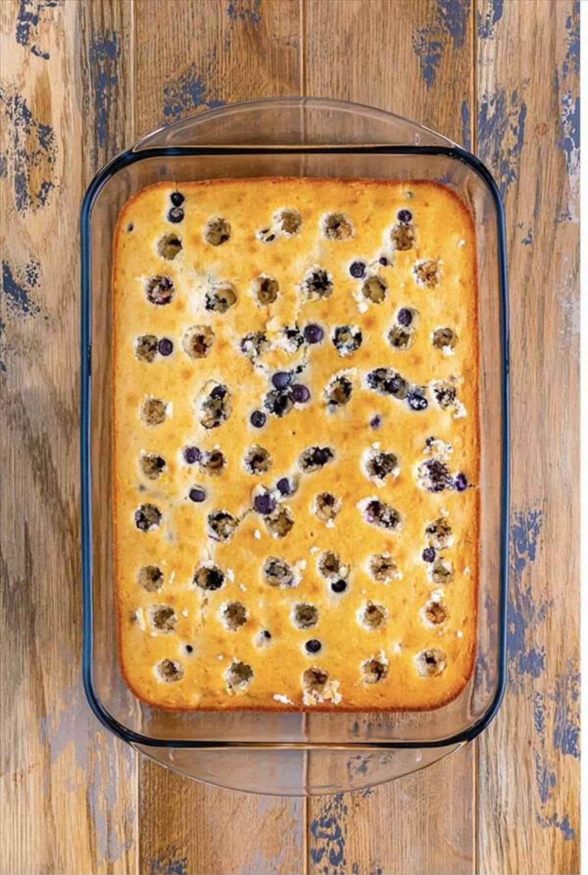 Holes poked all over the cooled lemon blueberry cake.