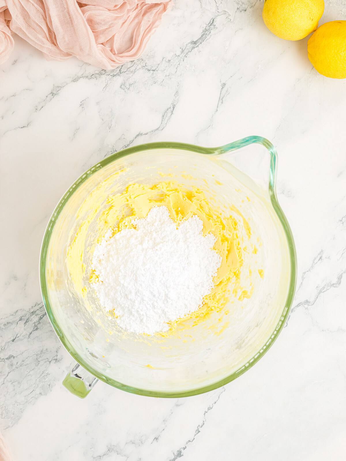 Adding powdered sugar to the lemon buttercream frosting.