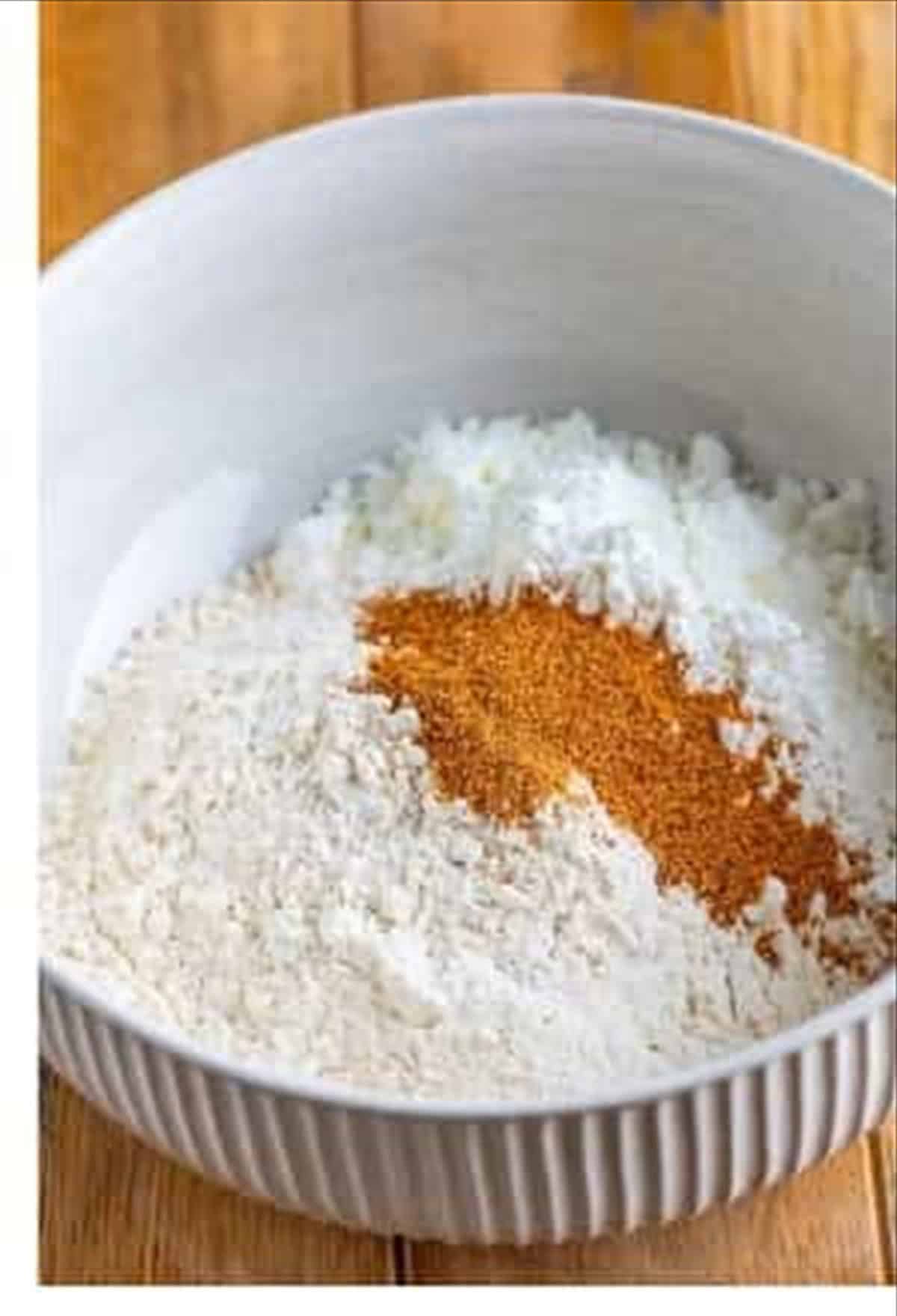 Flour, cornstarch, and creole seasoning combined in a bowl for the Louisiana fried chicken coating.