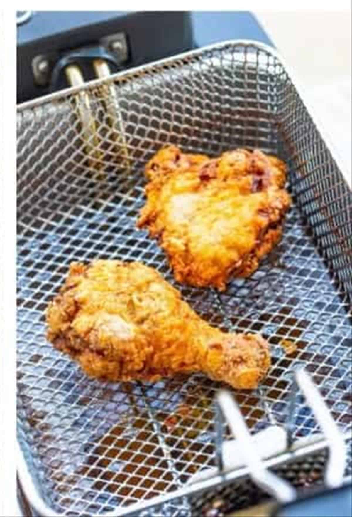 Louisiana fried chicken pieces frying to golden crisp in a deep fryer basket.