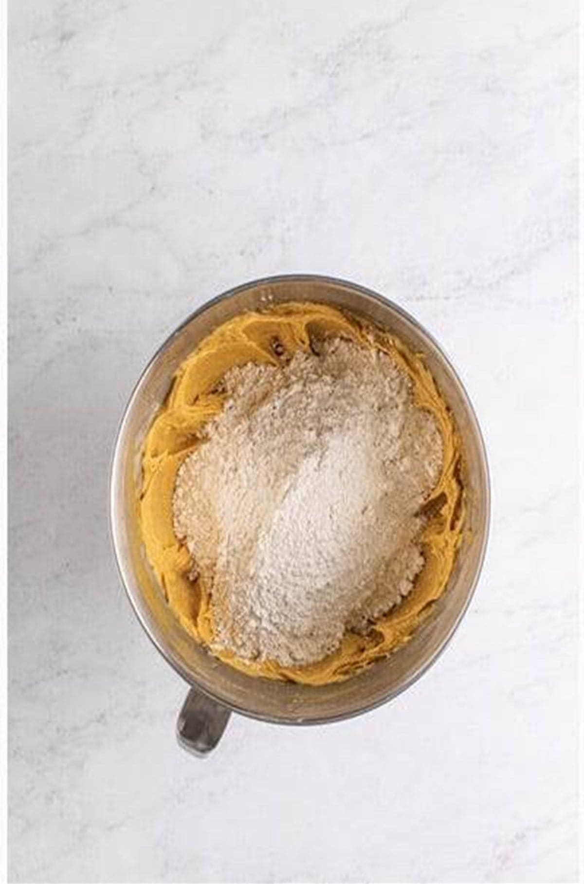 All-purpose flour added to peanut butter cookie wet mixture in stand mixer.