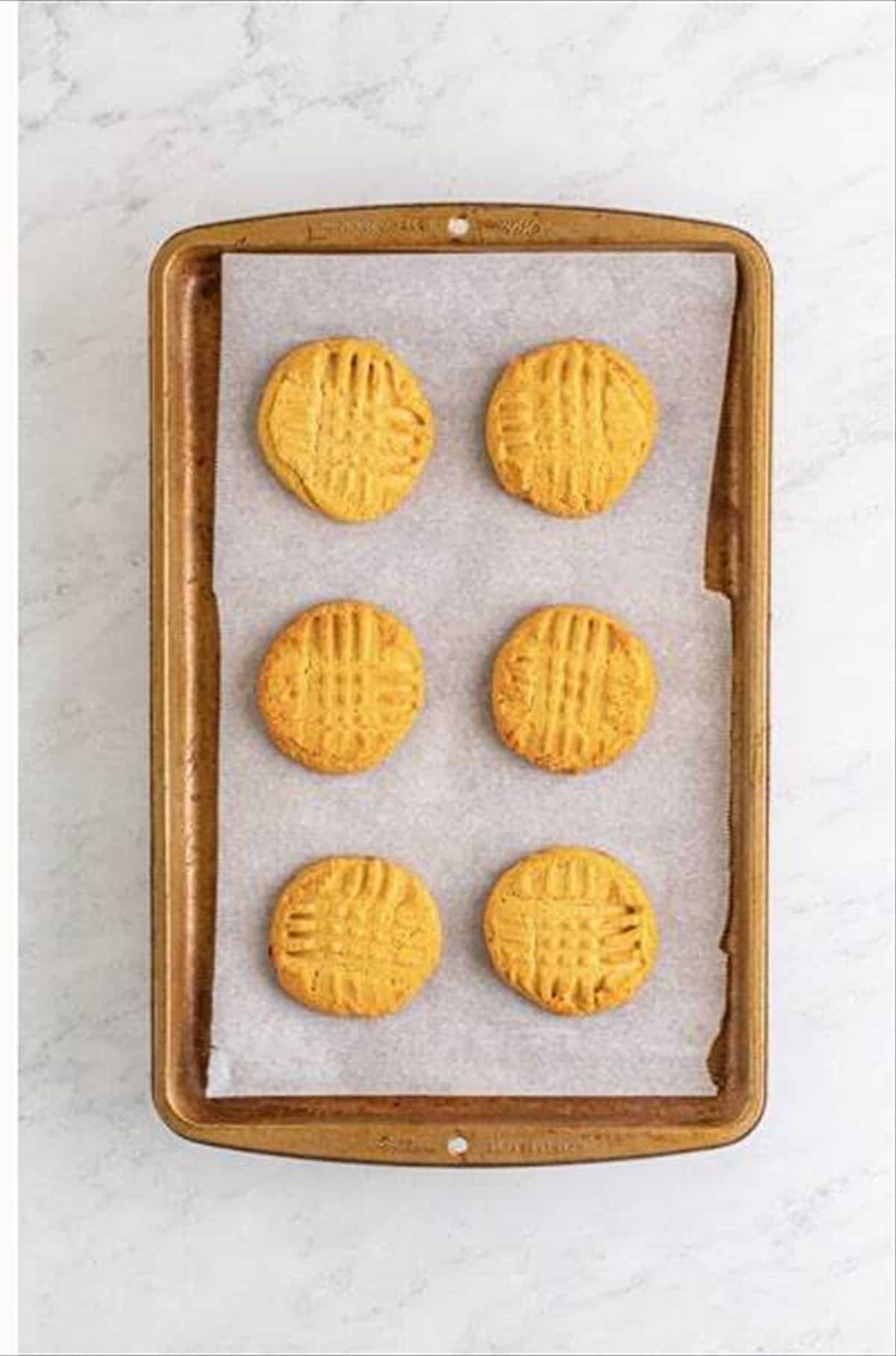 Golden brown lunch lady peanut butter cookies baked on a parchment-lined sheet pan.