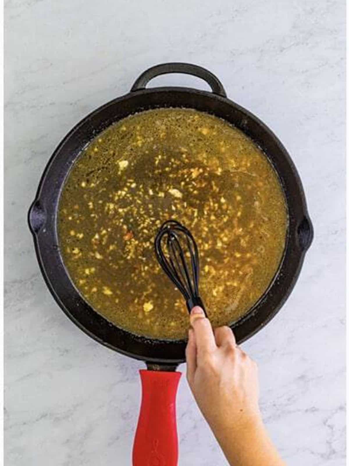 Adding chicken stock to deglaze the skillet for Marry Me Chicken.