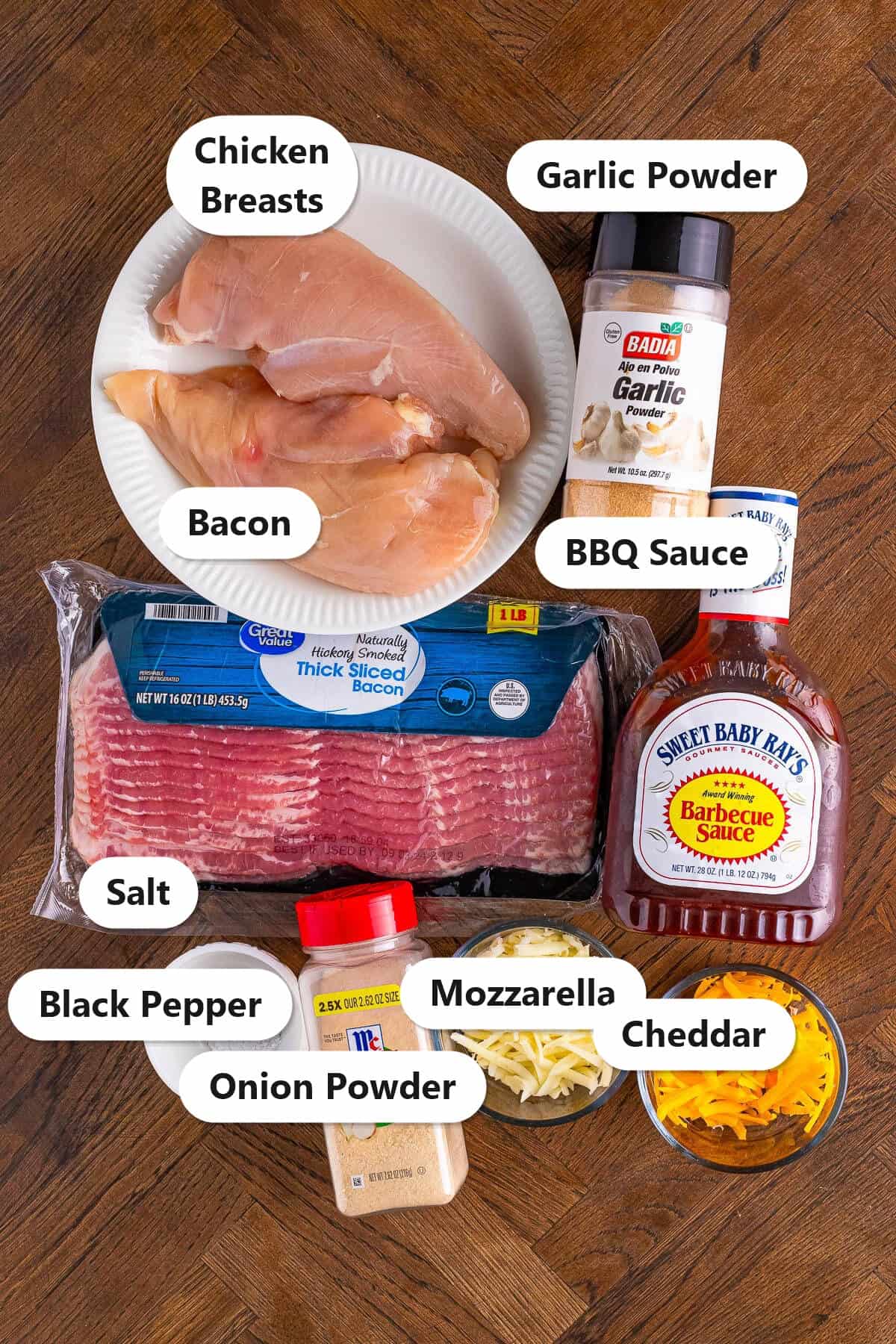 Labeled ingredients to make Monterey chicken including chicken breasts, bacon, BBQ sauce, garlic powder, onion powder, salt, pepper, mozzarella, and cheddar.
