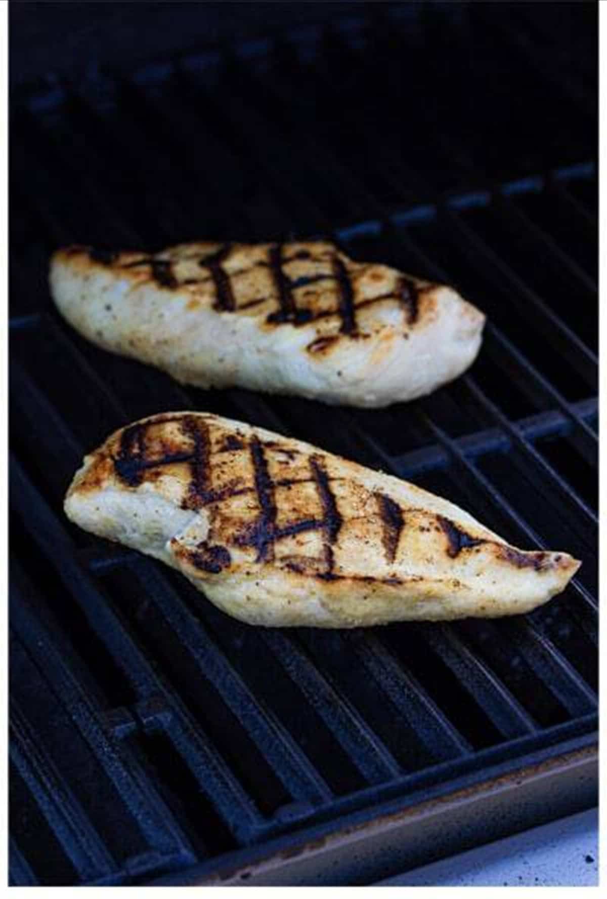 Grilled chicken breasts with grill marks on the grates.