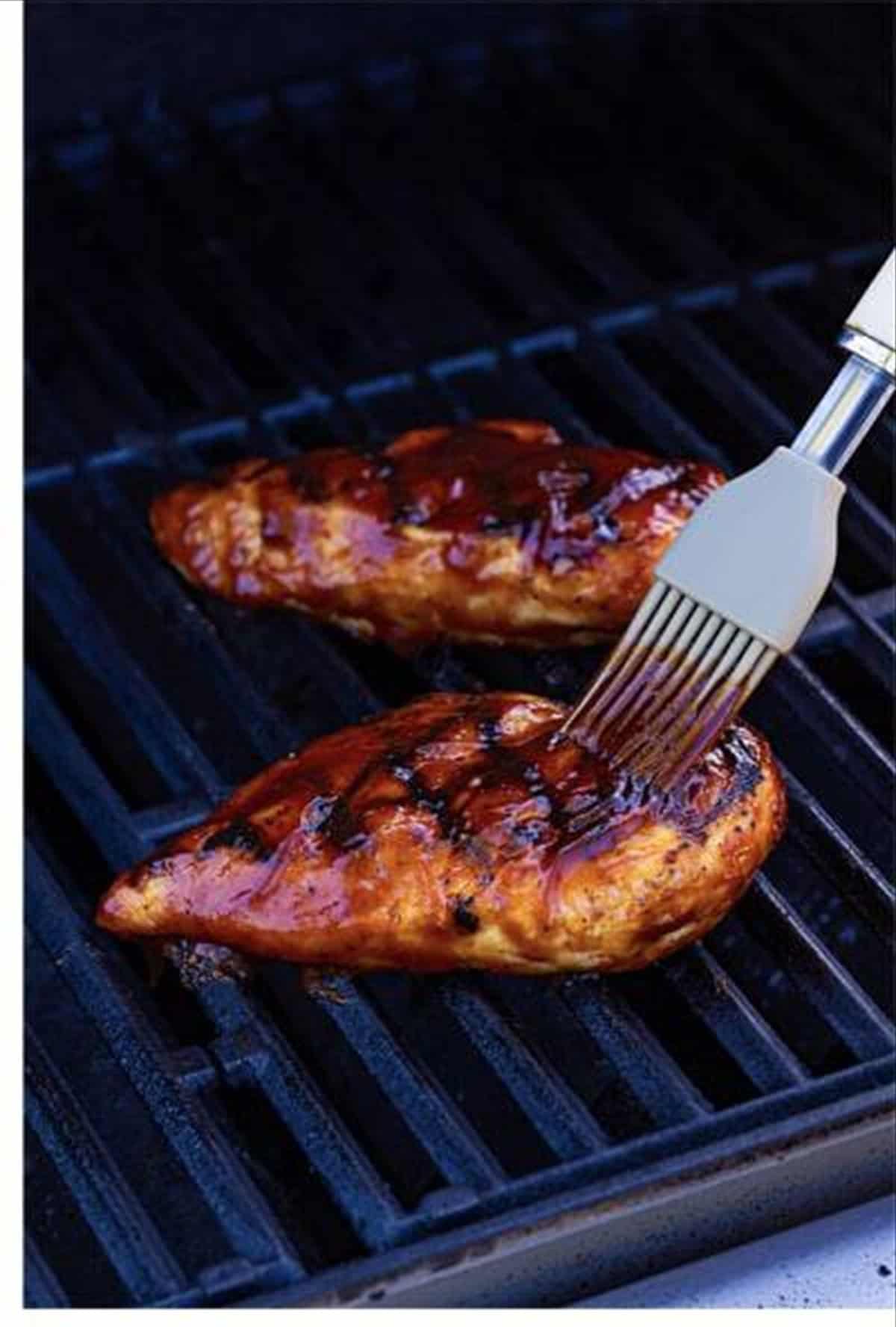 Basting the grilled chicken with BBQ sauce.